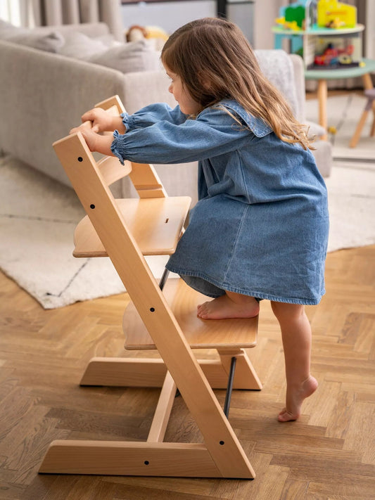 Child climbing onto a Stokke Tripp Trapp high chair at home